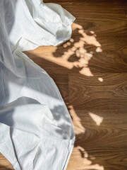 The play of light and shadow on a dark floor next to a white cloth