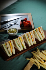 Assorted Club Sandwich isolated on wooden with mayonnaise dip and french fries bucket board side view of italian fast food on background
