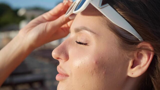 Beautiful woman taking off her sunglasses outdoors, closeup