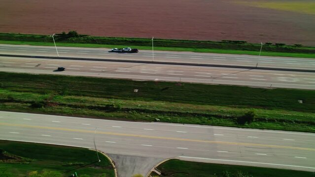Tracking a pick up truck car hauler carrier. Non CDL job transporting cars on wedge trailers. Above highway I-90 Rockford Illinois. Concept for hiring truck drivers and marketing of trucking business