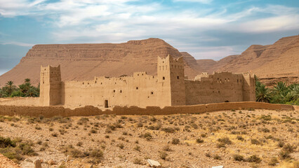 Fototapeta na wymiar Traditional Moroccan fortress made out of clay with high clay walls in the Atlas mountain gorge by Ziz river, Morocco