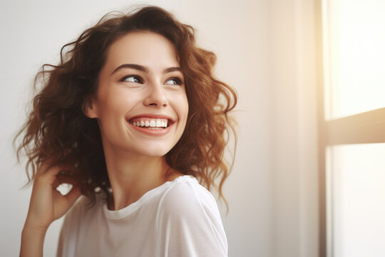 Woman with curly hair smiling in front of window. Perfect for showcasing joy and natural beauty.