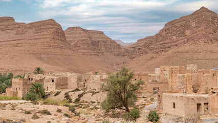 Traditional Moroccan clay houses with flat roofs, high clay walls and small windows in the Atlas mountain gorge by Ziz river, Morocco