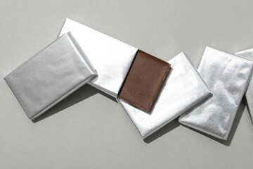 Chocolates in silver foil on gray background, top view