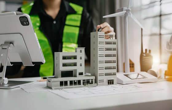 male architect  working with blueprints for sketching a construction project, green energy and solar panel concept.