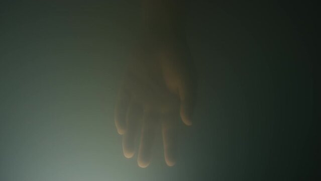 Macro close up of hand of unrecognizable lab grown foetus floating and disappearing in lab made amniotic fluid in artificial womb