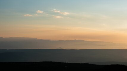 Stunning landscape featuring a picturesque sunset behind a series of snow-capped mountains.