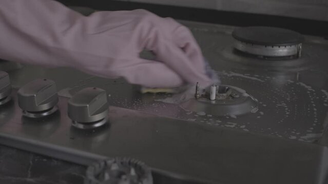 close-up of female hands in protective gloves washing a gas stove with a cleaning product video s-log