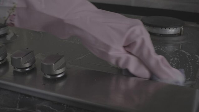 close-up of female hands in protective gloves washing a gas stove with a cleaning product video s-log