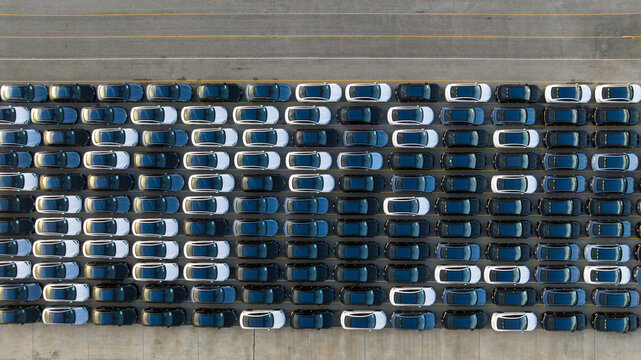 Aerial view new ev car on car park, Ev car loading, EV new cars stock at factory parking lot, Automotive industry, Logistics business. Import or export new cars at warehouse, Parking lot at port.