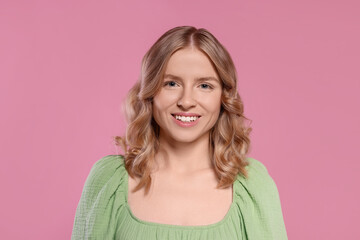 Portrait of beautiful woman with blonde hair on pink background