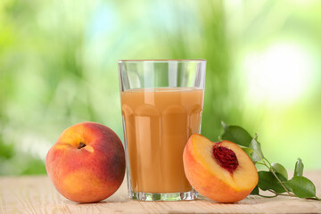 Tasty peach juice, fresh fruits and green leaves on wooden table outdoors