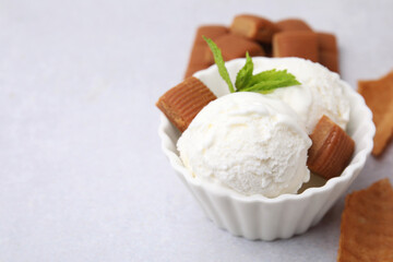 Scoops of tasty ice cream with mint and caramel candies on white table, closeup. Space for text