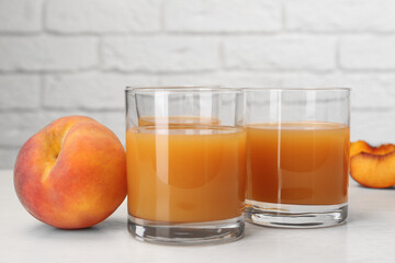 Glasses of delicious peach juice and fresh fruits on white wooden table