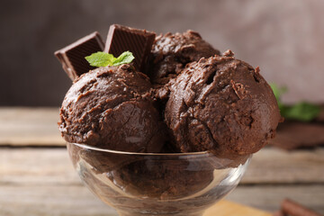 Tasty chocolate ice cream with mint in glass dessert bowl on table, closeup