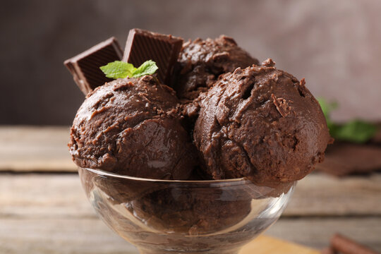 Tasty chocolate ice cream with mint in glass dessert bowl on table, closeup
