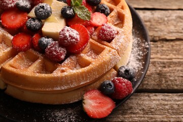 Tasty Belgian waffles with fresh berries, cheese and powdered sugar on wooden table, closeup