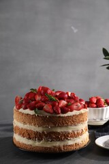 Tasty cake with fresh strawberries and mint on table against gray background, space for text