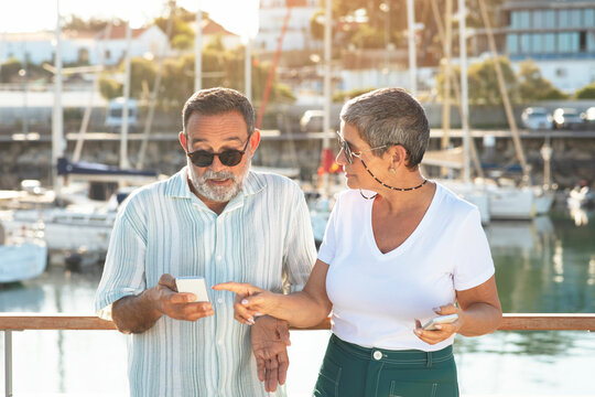 Mature woman confronting husband about photos on phone at marina