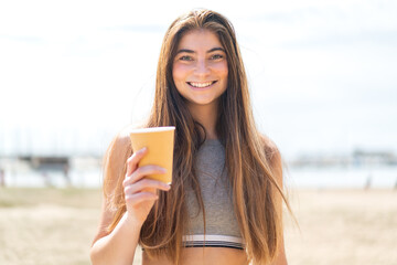 Young pretty caucasian woman holding a take away coffee at outdoors smiling a lot