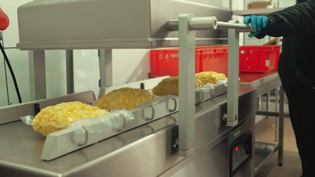 Food industry employee using a Reduced Oxygen Packaging machine to pack fresh potatoes into specialistic plastic bags. High quality 4k footage