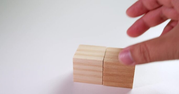 Aranging and stacking up blocks with a tiny wooden toy house on top of it.