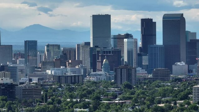 Cityscape of Denver with Colorado mountain ranges backdrop; skyscrapers. Long zoom lens on drone. Aerial shot with capitol building.