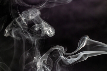 Fancy beautiful shapes from smoke in the air on a black background close-up	
