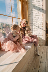 two cute little sisters with bear toys playing near window