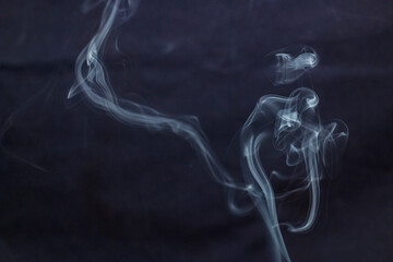 Smoke curls up from incense on a black background	
