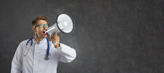 Male healthcare professional loudly announces important information through loudspeaker. Doctor on gray background near free space for text. Concept of medical marketing and sales. Banner. - obrazy, fototapety, plakaty