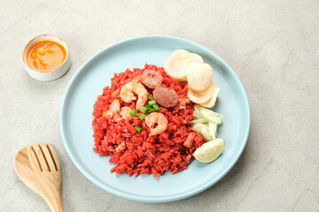 Nasi Goreng Merah, traditional food from Makassar, Indonesia. Fried rice with tomato sauce, shrimp, meatballs and egg. Served with pickled cucumber, chili sauce and lime
