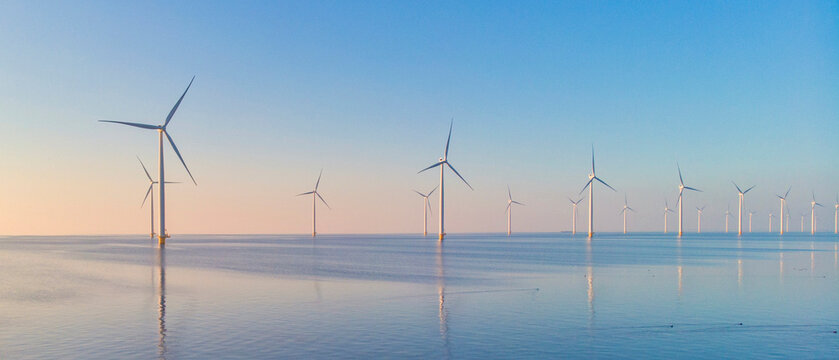 Windmill park in the ocean, drone aerial view of windmill turbines generating green energy electric,