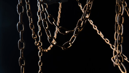 Macro shot of a rusty old metal chain on a black background. The chain links are covered in rust...