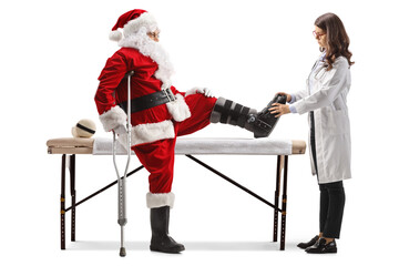 Female doctor checking santa claus with a foot brace and crutch