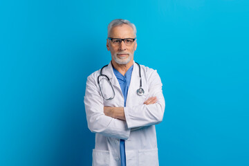 Portrait of confident elderly doctor posing in medical uniform - obrazy, fototapety, plakaty