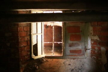Walled basement window with broken panes and some daylight falling in
