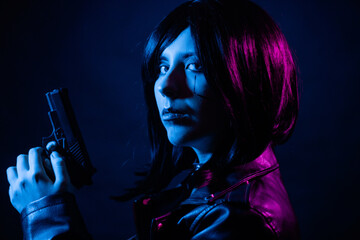 Portrait of a young woman with a bob hairstyle in a black leather jacket and a spiked collar with a gun in her hands, posing isolated on a dark background, cyberpunk concept.