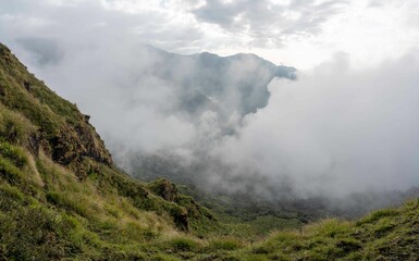 a steep slope with a fog covering the mountains below it