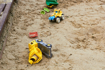 Children's plastic toys concrete mixer and tractor on the sand. Sandbox.