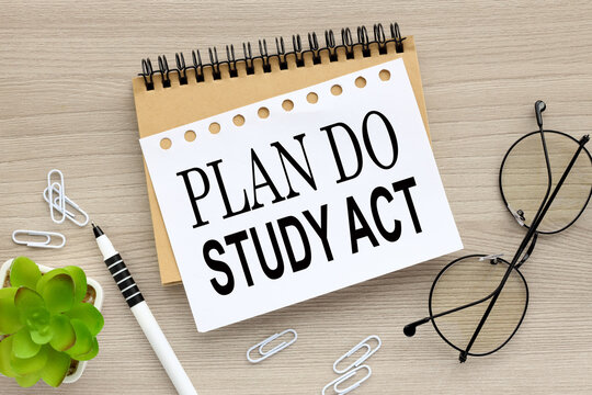 Plan Do Study Act wood background words on notebook