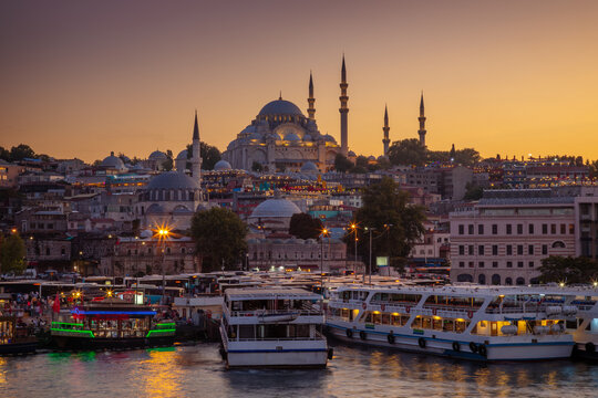 Historic Suleymaniye Mosque at dusk and the Golden Horn with ferries. Istanbul, Turkey.