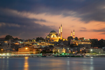 Historic Suleymaniye Mosque at dusk and the Golden Horn with ferries. Istanbul, Turkey.