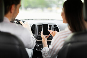 Back view couple having car trip together, using cell phone