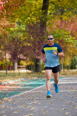 Portrait of a middle-aged man running in the park on an autumn day.