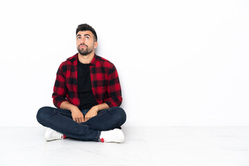 Young handsome man sitting on the floor and looking up