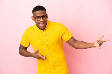 Young latin man isolated on pink background making guitar gesture