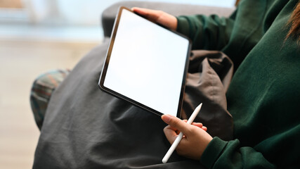 Close up shot young woman hands holding digital tablet with blank screen sitting on couch at home