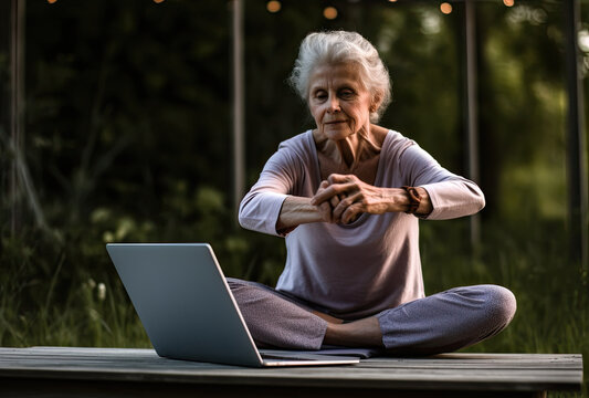 Woman sitting in yoga class on fitness mat while watching fitness video using laptop during video training. online class concept
