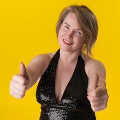 Portrait of curvy mature blonde woman in black evening gown with spangles and neckline on bright...